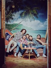 Die fünf Jungs der Band anders sitzen auf einer Couch vor einer Wand mit Hawaii-Tapete. 